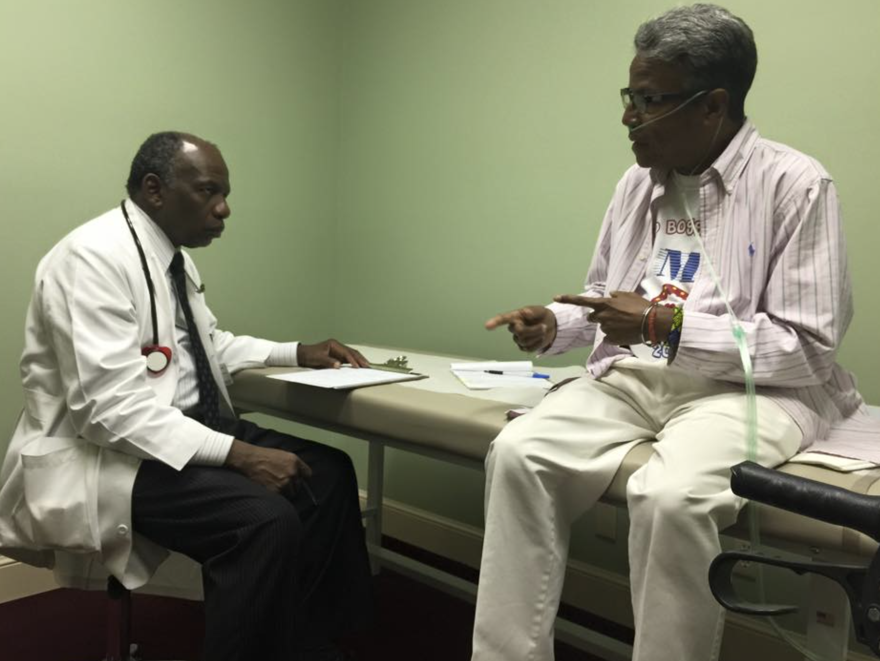 Juan Caballero (right) sits in triage and speaks with FSCDR's Hematologist, Dr. Gershwin Blyden (left). Mr. Caballero was fully dependent on oxygen at the time. This photo was taken February 27, 2015.