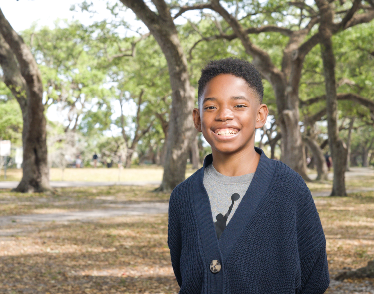 Picture of a kid with trees behind him
